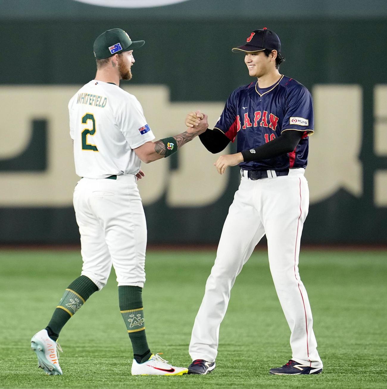 試合前、エンゼルスのチームメートでオーストラリア代表のホワイトフィールド（左）とあいさつを交わす大谷（共同）