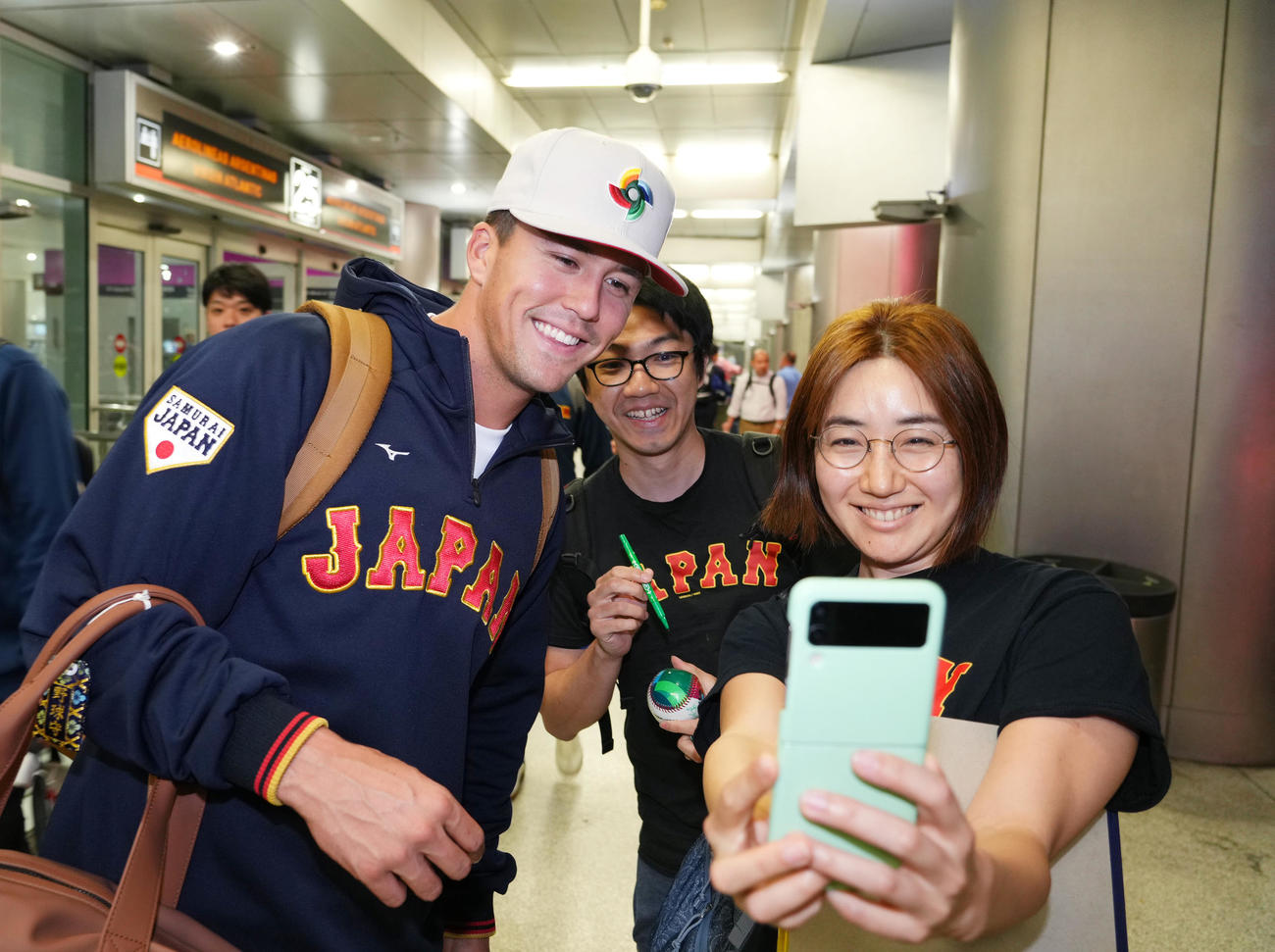 準決勝・決勝が行われる米国マイアミに到着し、ファンと記念写真に納まるヌートバー（左）（撮影・菅敏）