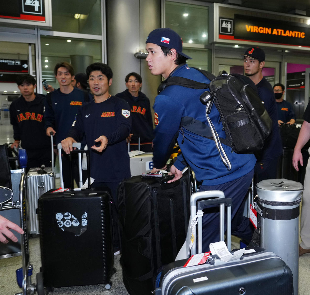 チェコの帽子をかぶり米国マイアミに到着し、荷物を運ぶ大谷。後方左から近藤、源田、ダルビッシュ（撮影・菅敏）