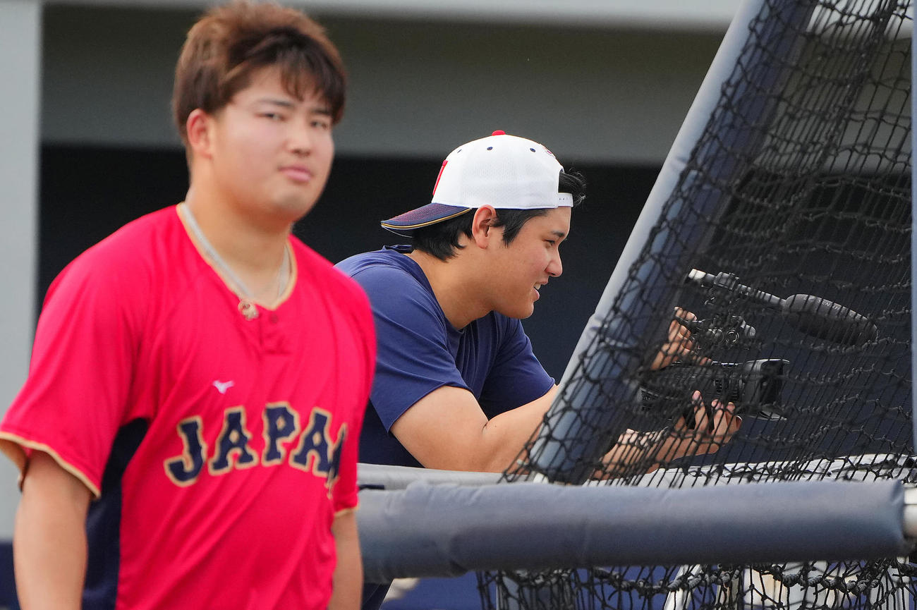 村上（左）のフリー打撃をハンディーカメラで撮影し笑みを浮かべる大谷（撮影・垰建太）