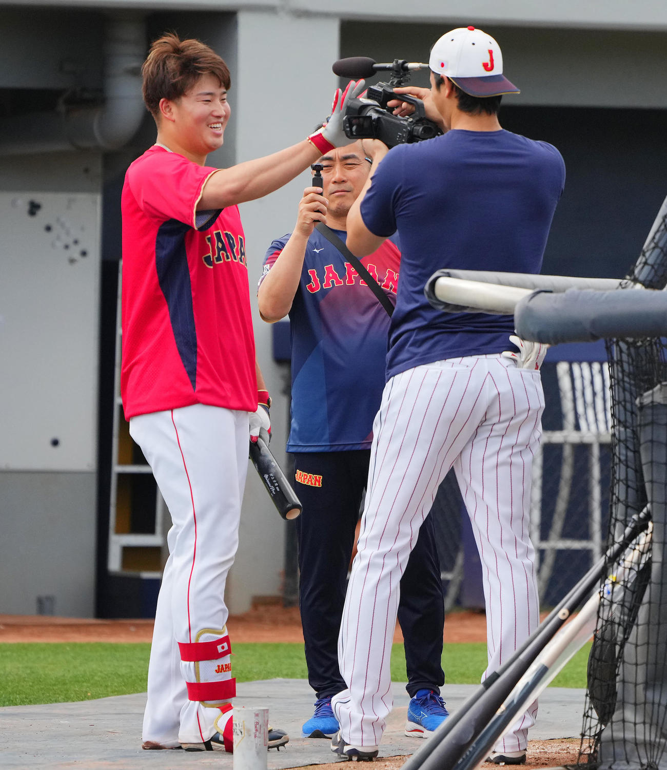 打撃練習の合間に大谷（右）にカメラを向けられ照れ笑いを浮かべる村上（撮影・垰建太）