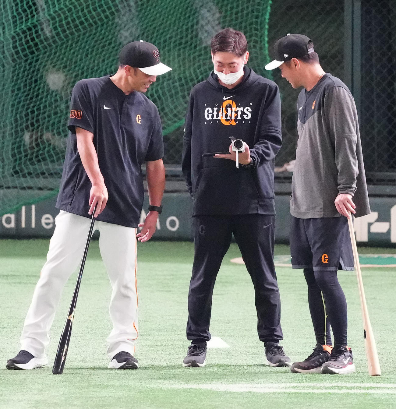 巨人対DeNA　試合前練習中、WBC準決勝の中継をスマホで見る巨人阿部ヘッド兼バッテリーコーチ（左）と元木作戦兼内野守備コーチ（右）（撮影・江口和貴）
