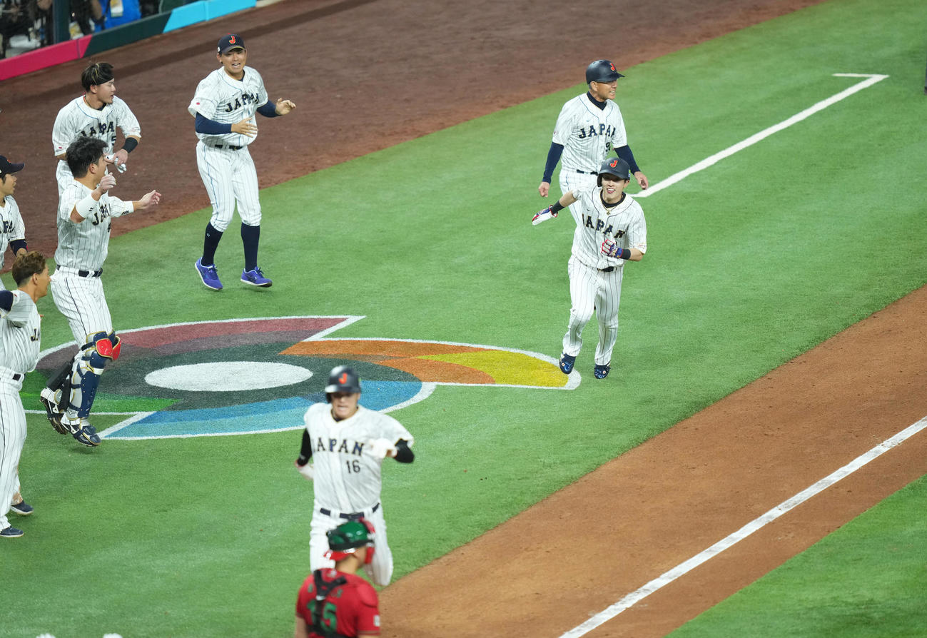 日本対メキシコ　9回裏日本無死一、二塁、村上宗隆の逆転の2点適時二塁打で舌を出して激走しサヨナラの生還を果たす周東。手前は一塁走者大谷（撮影・菅敏）