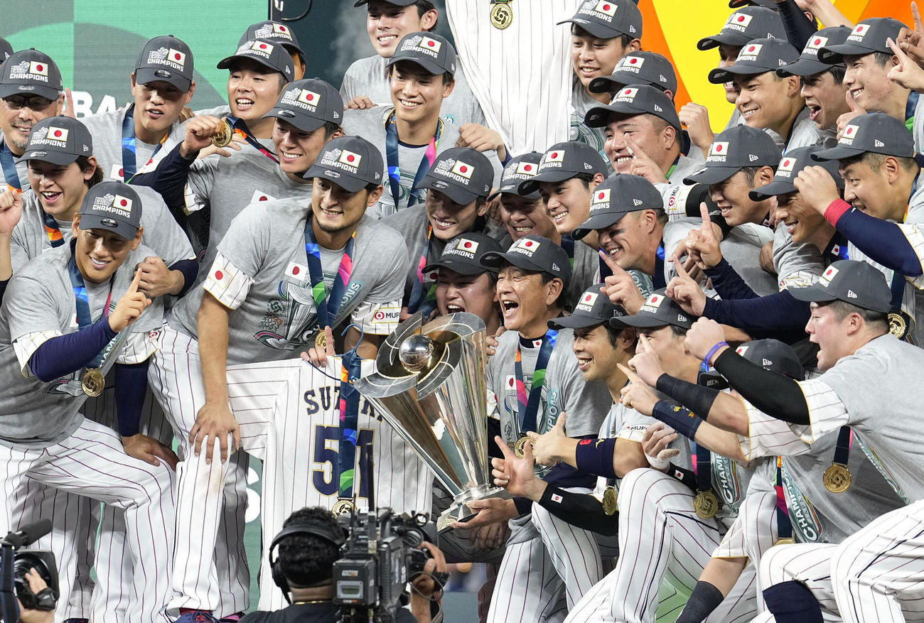 第5回WBCで米国を破って優勝を果たし、トロフィーを手に写真に納まる栗山英樹監督（中央）と日本の選手たち（共同）