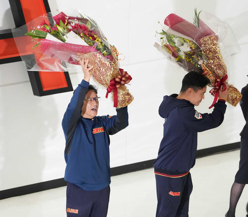 帰国し、受け取った花束を手にファンの声援に応える侍ジャパンの栗山監督（左）と中村（撮影・鈴木みどり）