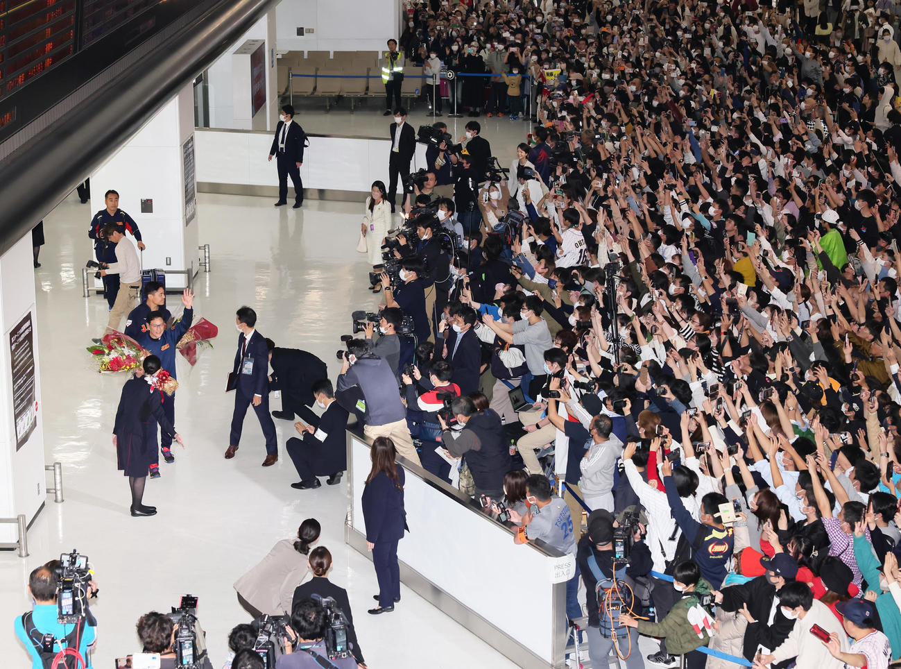 帰国し、大勢のファンの出迎えに手を振って応える日本の栗山監督（中央左）（撮影・足立雅史）