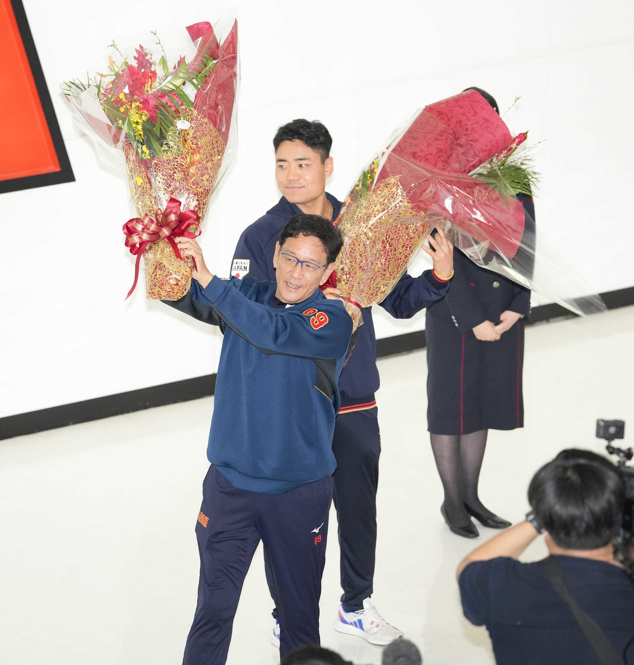 成田空港に到着し、花束を手にファンの声援に応える侍ジャパン栗山監督（手前）と中村（撮影・鈴木みどり）