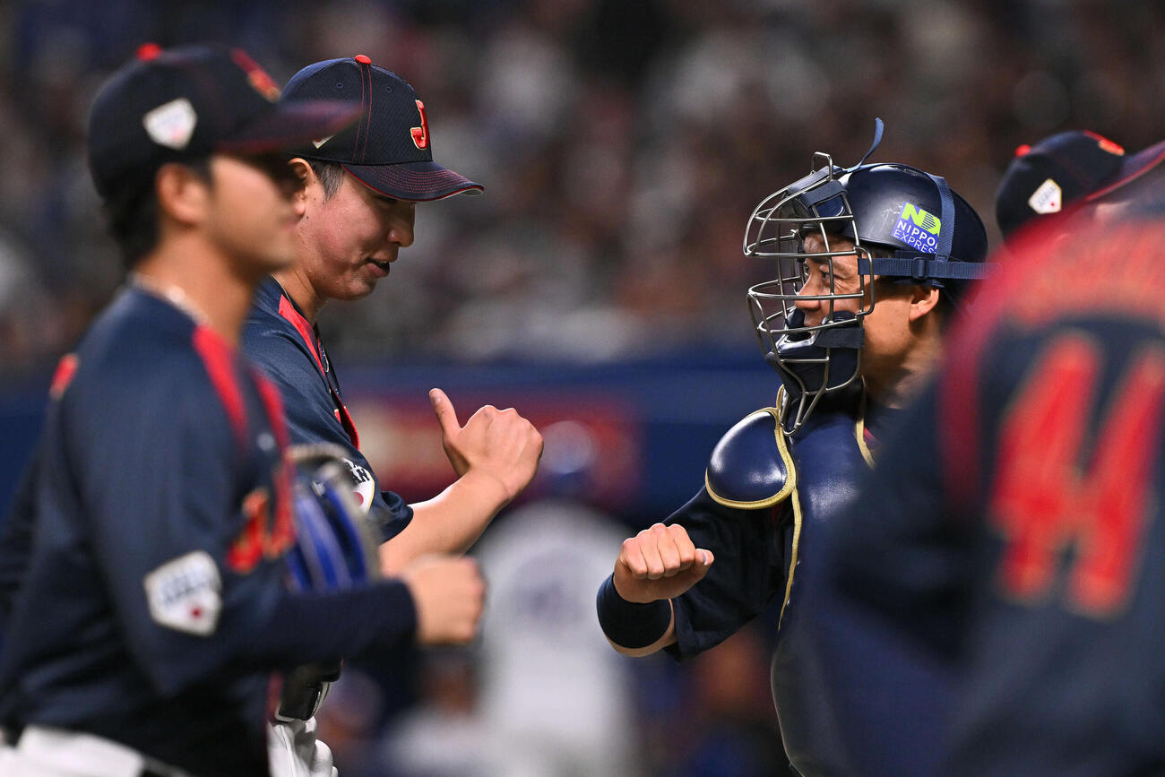 中日対日本　7回裏を投げ終えた日本4番手の藤平（中左）は中村とタッチを交わす（撮影・滝沢徹郎）