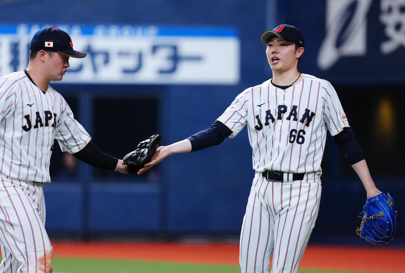 日本対オリックス　8回裏オリックスの攻撃を無失点に抑えタッチを交わす松本裕（右）と牧（撮影・垰建太）