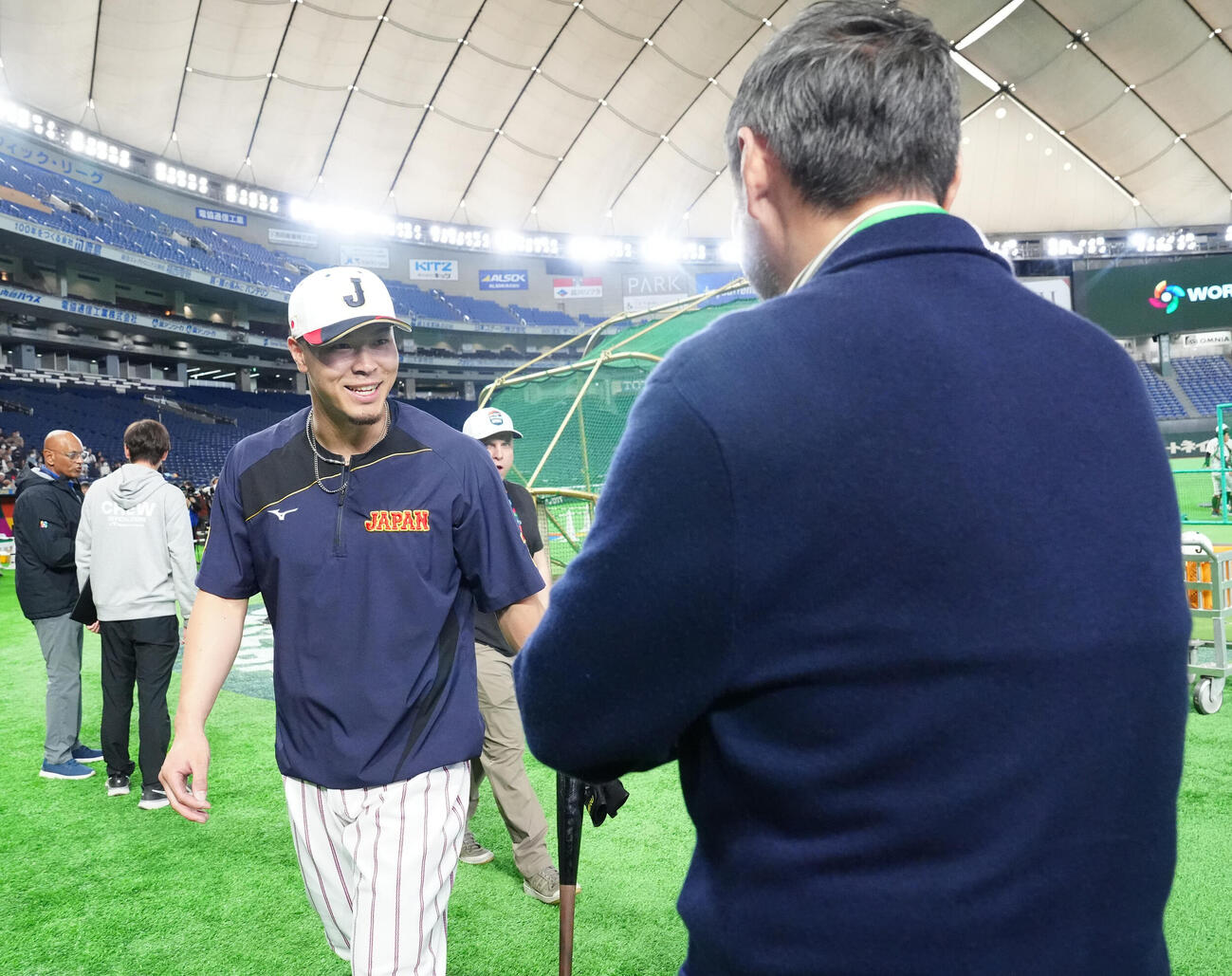 WBC公式練習を見学する渡辺謙（右）にあいさつする佐藤（撮影・江口和貴）