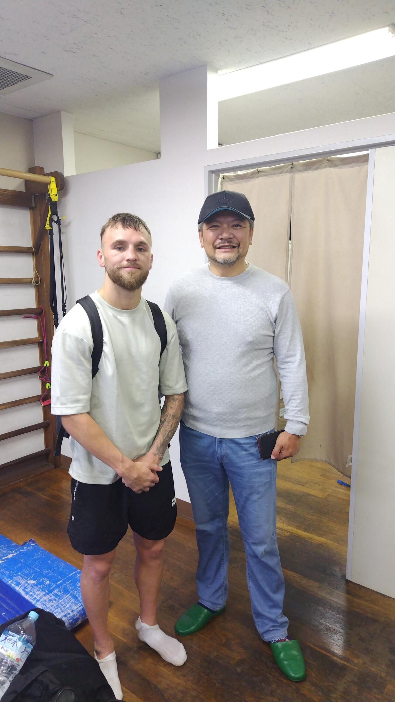 公開練習後、西田凌佑が所属する六島ジムの枝川孝会長（右）と記念写真に収まるサム・グッドマン（2026／09／21、帝拳ジム）