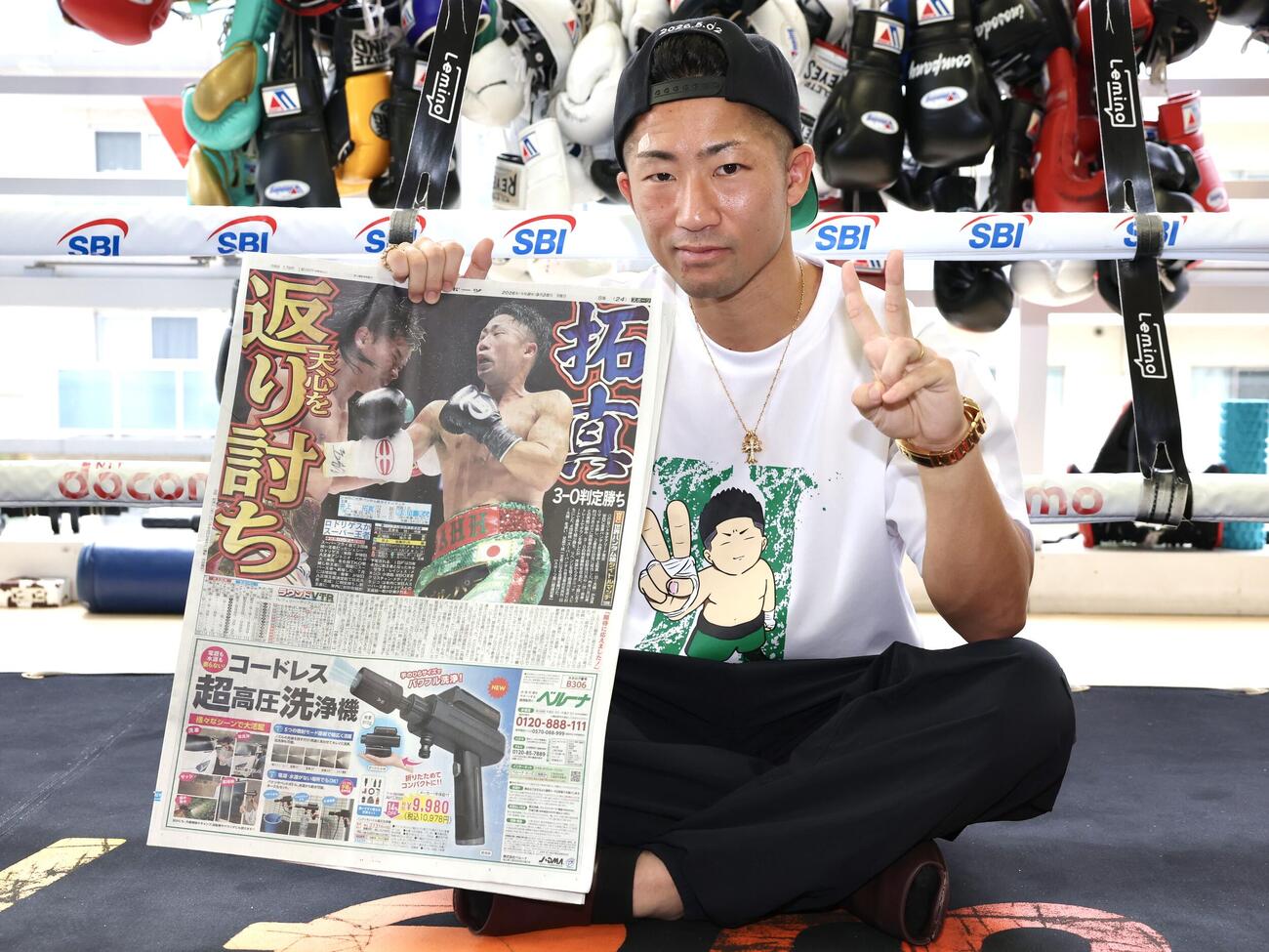 那須川天心戦から一夜明け、本紙を手に笑顔を見せる井上拓真（撮影・宮地輝）