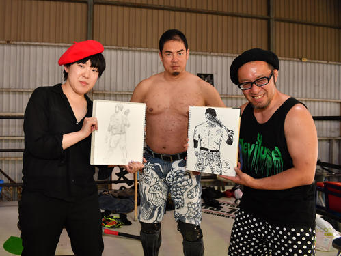 高場泉穂記者(左)と選手兼レフェリーフランク篤(右)がプロレスラー伊東竜二の背中のデッサンを披露する