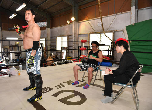 高場泉穂記者(右)と選手兼レフェリーのフランク篤(中央)がプロレスラー伊東竜二の背中をデッサンする（撮影・柴田隆二）
