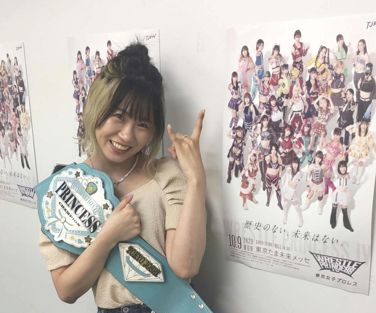 9日八王子大会のポスターの横でポーズを取る辰巳リカ（撮影・松熊洋介）