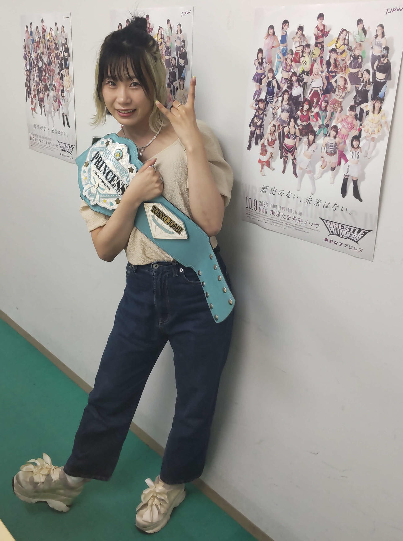 9日八王子大会のポスターの横でポーズを取る辰巳リカ（撮影・松熊洋介）
