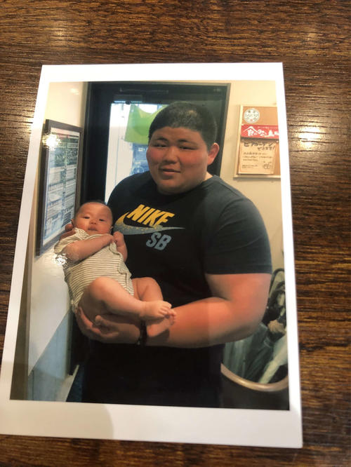 扇雀（せんじゃく）食堂の店員古瀬さんの赤ちゃんを抱っこする新十両の落合（撮影・平山連）