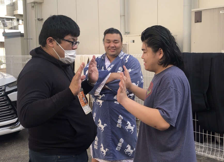 記者と手押し相撲を楽しむ竹内（右）。中央は霧島