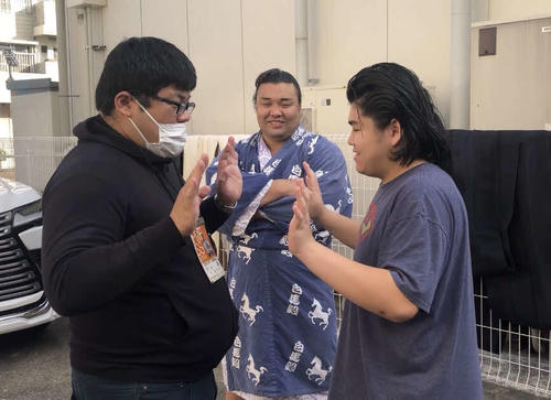 記者と手押し相撲を楽しむ竹内（右）。中央は霧島