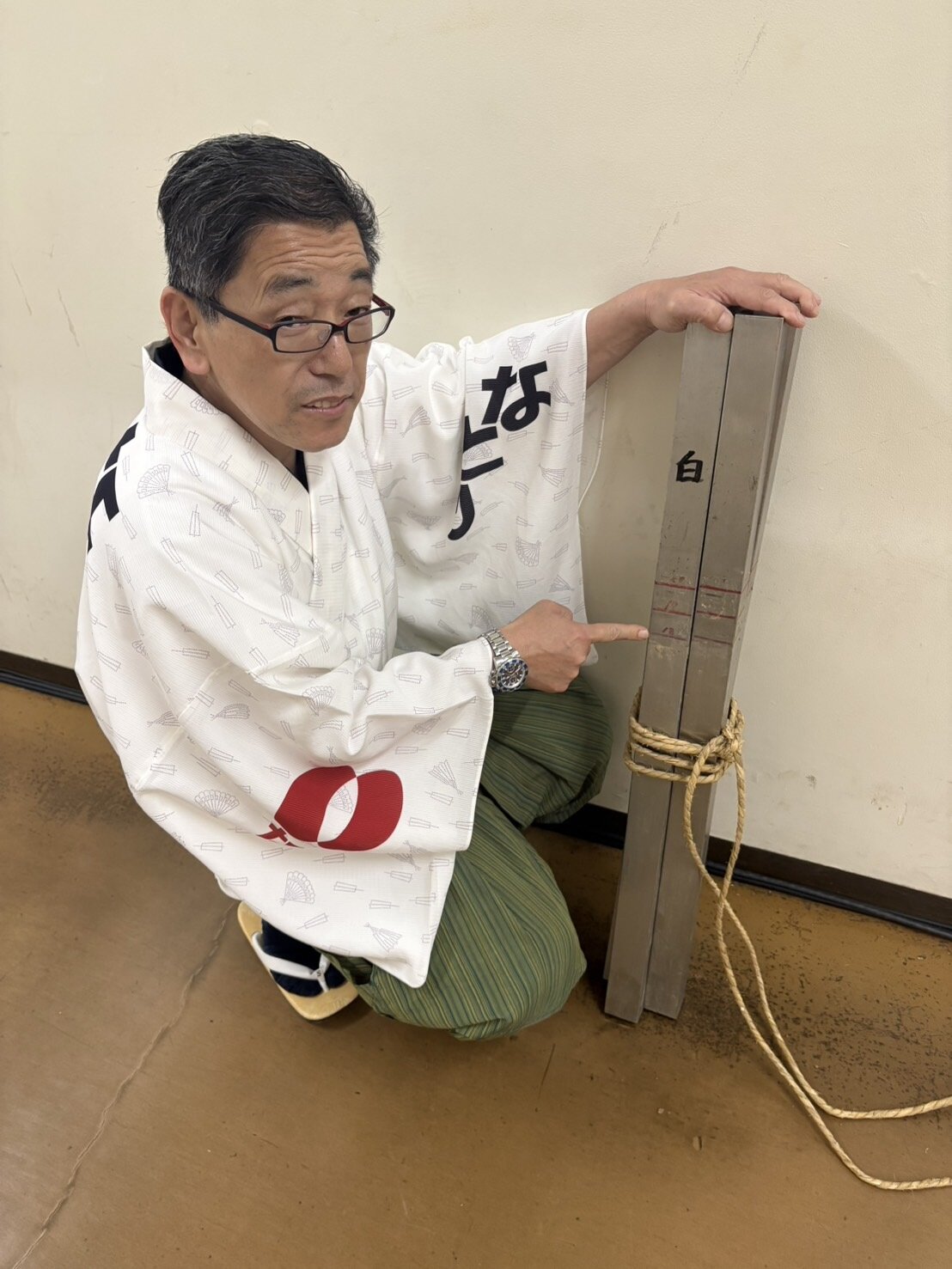 土俵築の監督を務めている呼び出しの吾郎。1尺8寸を意味する18のメモリを指さしている
