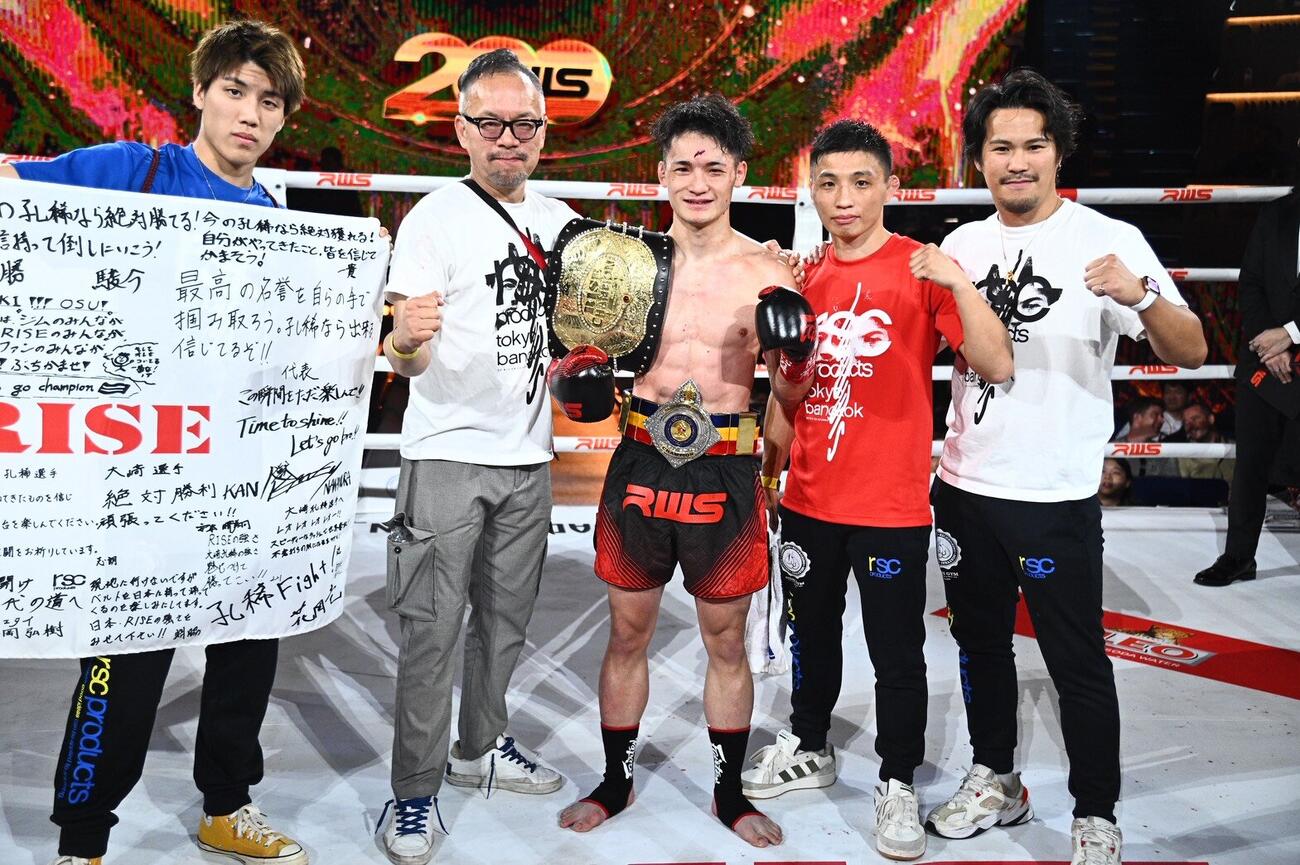 兄の大﨑一貴（右から2人目）や大石陽一郎会長（同4人目）らと写真に納まる大﨑孔稀（中央）（C）RISE