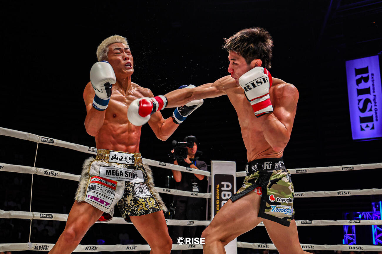山田貴紀に強烈なパンチを打ち込む玖村将史（右）（C）RISE