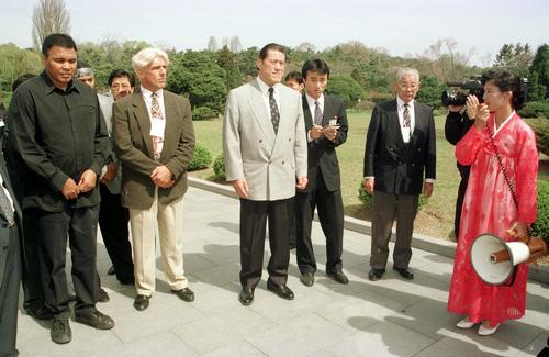 平和のための平壌国際体育・文化祝典」に参加するため北朝鮮を訪れ万景台の金日成の生家に立ち寄り案内人の説明を聞く（左から）ムハマド・アリ、リック・フレアー、アントニオ猪木（1995年4月29日撮影）
