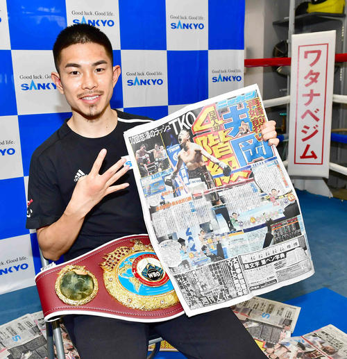 一夜明け会見を終え本紙1面を手に笑顔で記念撮影に臨む井岡（撮影・小沢裕）
