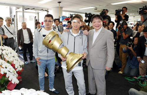 一夜明けの会見後、アリ・トロフィーを抱え、記念撮影をする井上尚（中央）。左は父・真吾トレーナー、右は大橋会長（撮影・狩俣裕三）