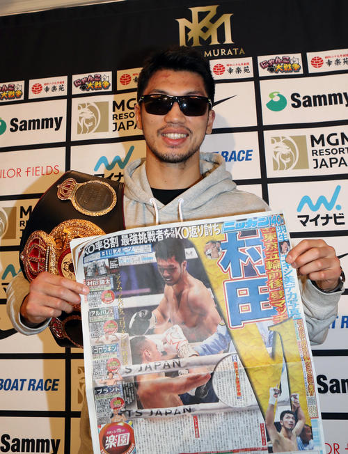 一夜明け会見後、本紙一面を手に笑顔を見せる村田（撮影・狩俣裕三）