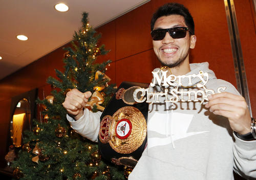 一夜明け会見後、クリスマスツリーを背に笑顔を見せる村田（撮影・狩俣裕三）