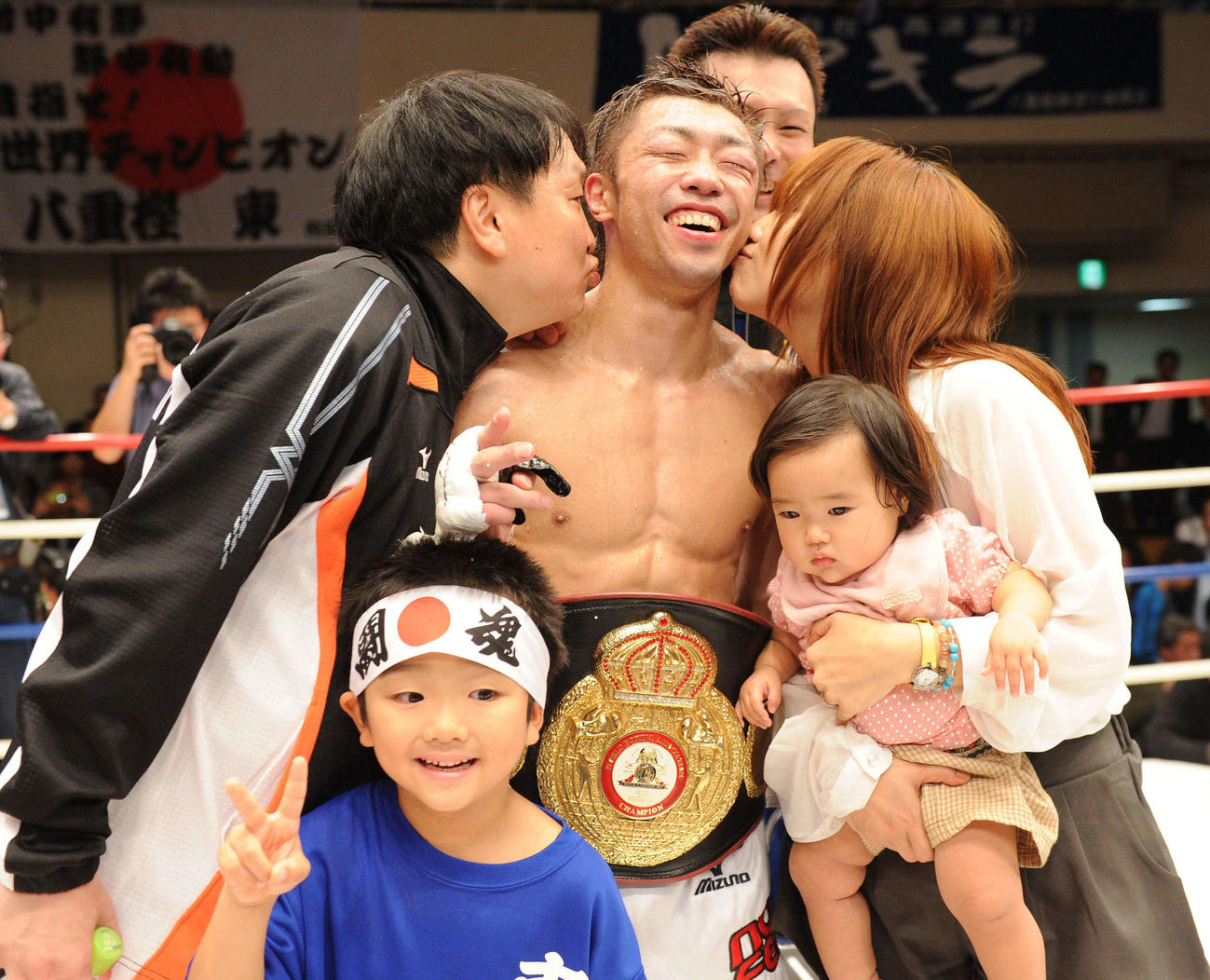11年10月24日、WBA世界ミニマム級で新チャンピオンに輝いた八重樫（中央）は大橋会長（左）と彩夫人からキスの祝福を受ける。前列は長男の圭太郎くんと長女の志のぶちゃん