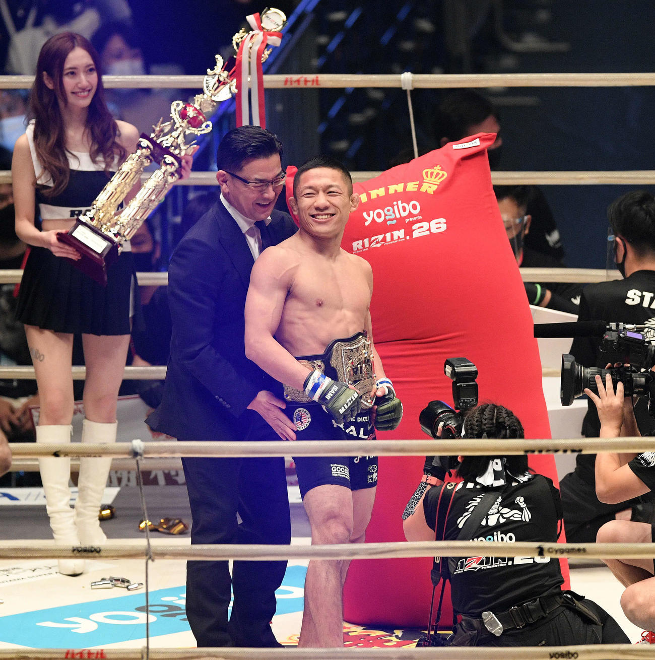 チャンピオンとなり榊原CEO（左）からベルトを巻いてもらう堀口（撮影・滝沢徹郎）