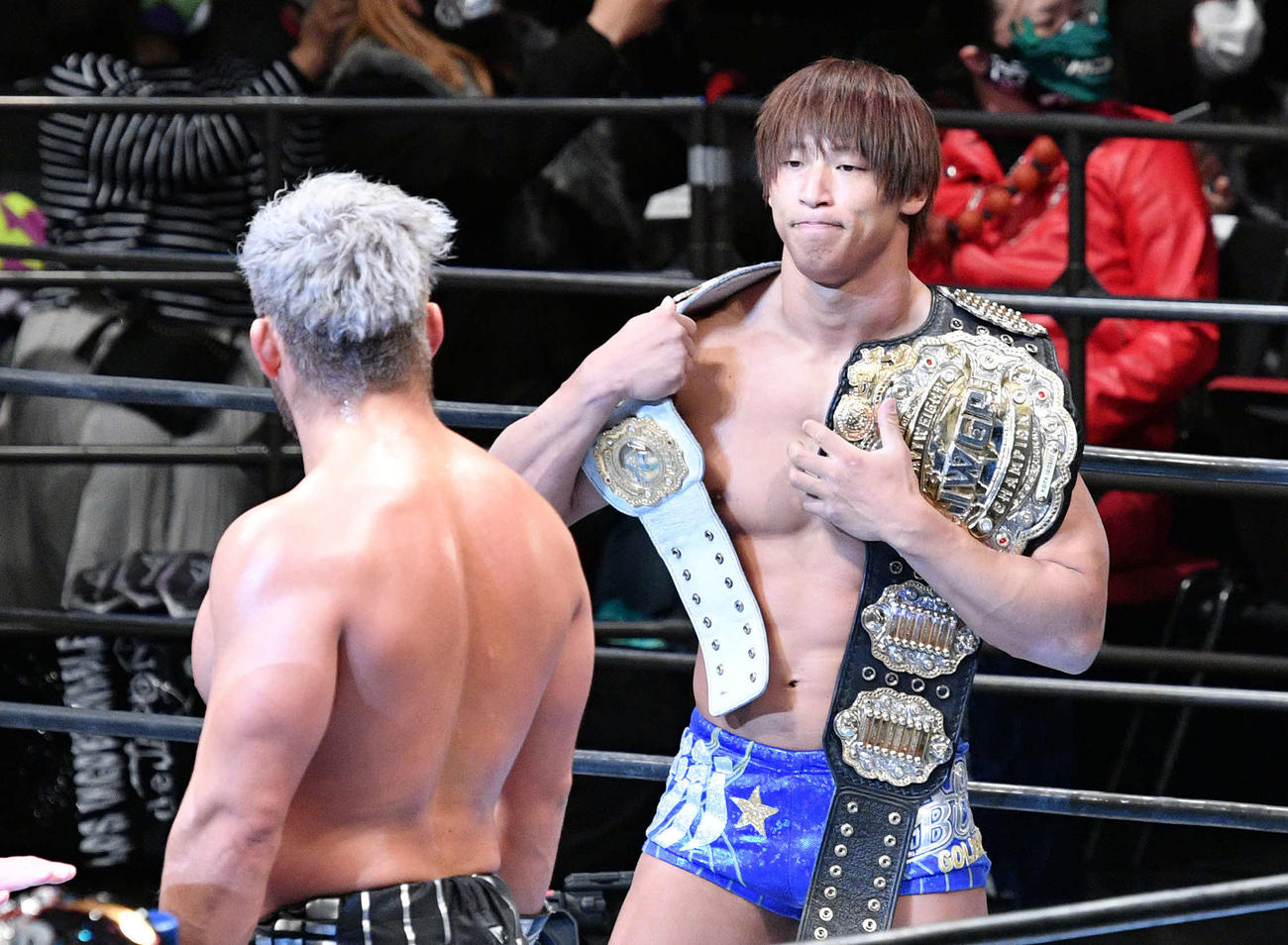 試合後、2本のベルトを肩にSANADA（手前）をにらみつける飯伏（撮影・滝沢徹郎）