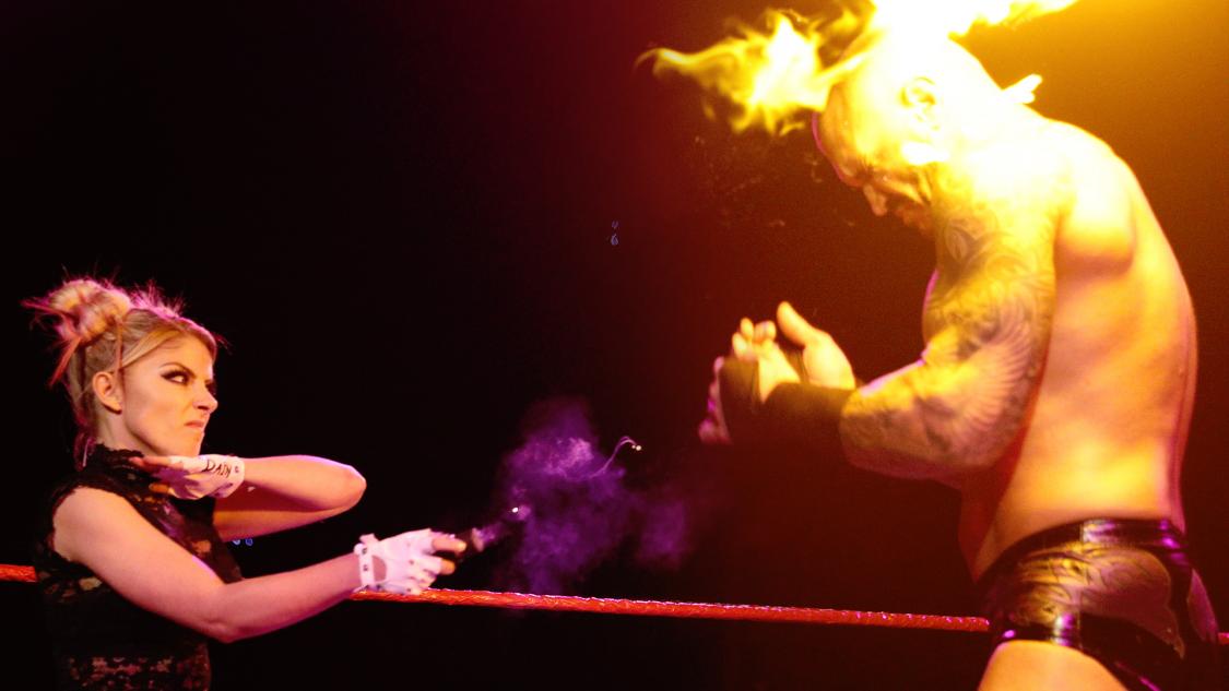 アレクサ・ブリス（左）に火を向けられたランディ・オートン（C）2021WWE,Inc.AllRightsReserved.
