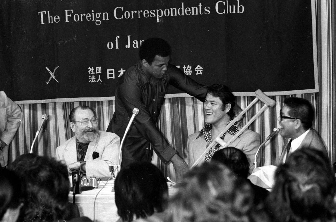 来日したムハマド・アリ（中央左）は外国人記者クラブでの会見で松葉づえをプレゼントしたアントニオ猪木に詰め寄る