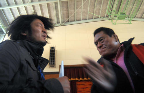 東日本大震災　アントニオ猪木（右）の「闘魂注入」に顔を歪める避難している人＝2011年４月５日
