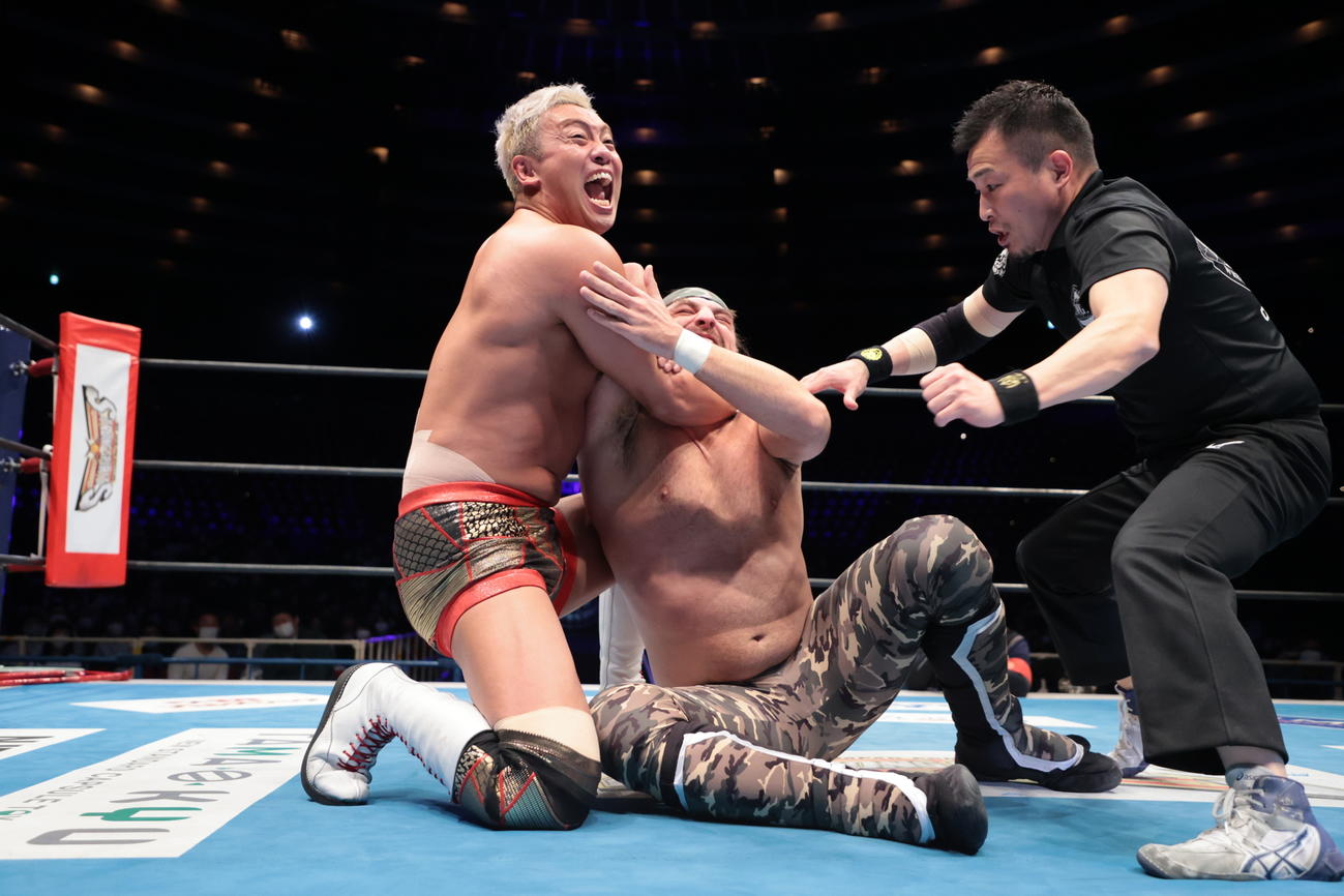 オーエンズ（中央）をマネークリップで絞めあげるオカダ（左）（提供：新日本プロレス提供）