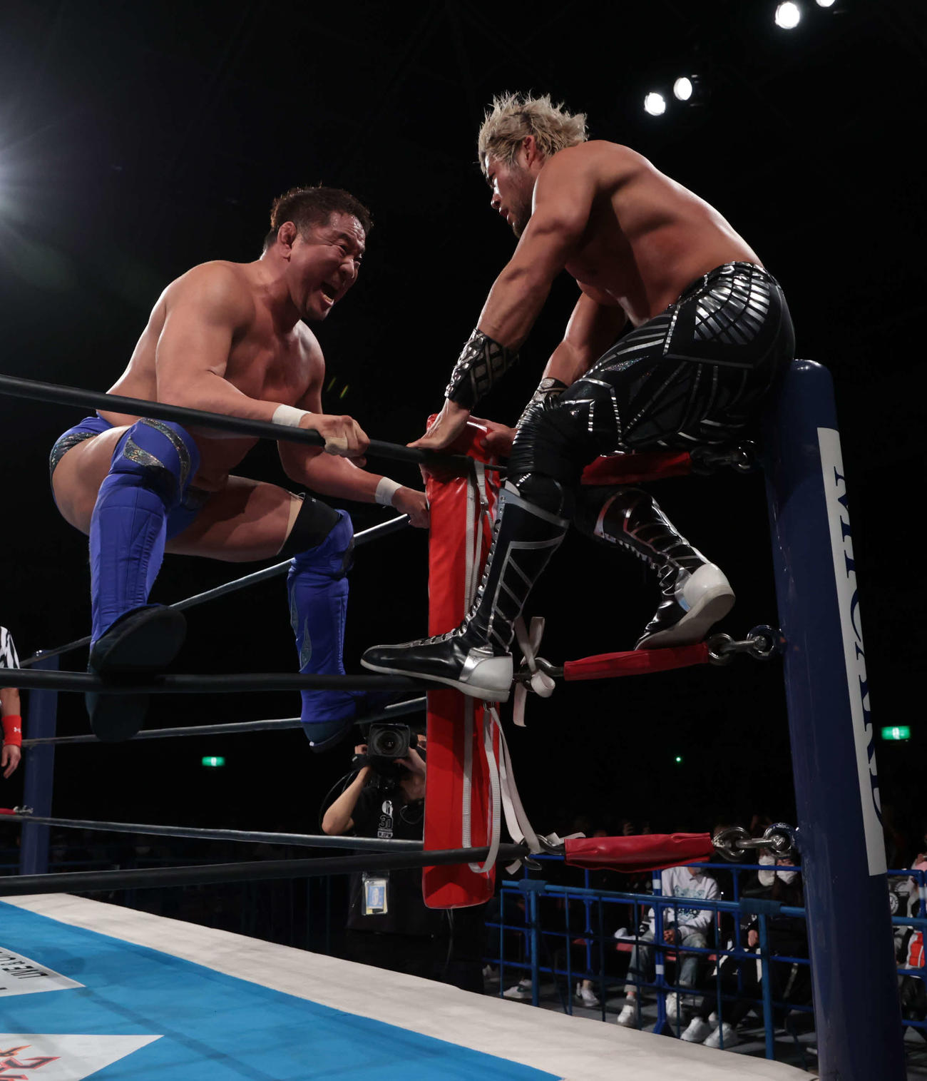 新日本プロレス尼崎大会　コーナーのSANADA（右）に襲いかかる永田裕志（新日本プロレス提供）