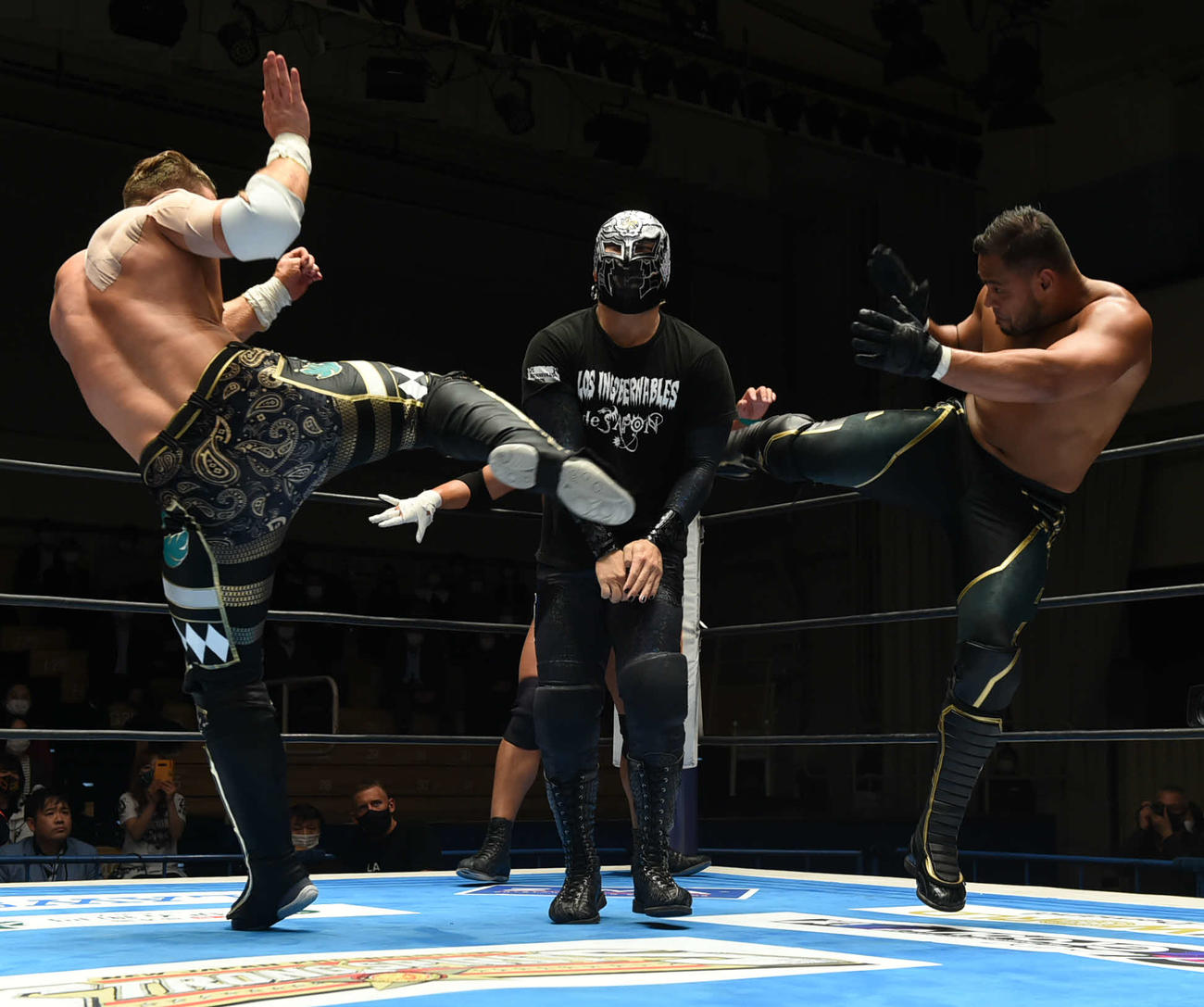新日本プロレス後楽園大会　アーロン・ヘナーレ（右）とウィル・オスプレイ（左）は、BUSHIにサンドイッチ式キックをさく裂させる（新日本プロレス提供）