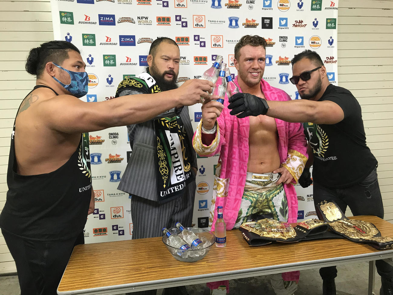 新日本プロレス福岡大会　IWGP世界ヘビー級の初防衛を果たしたウィル・オスプレイ（右から2人目）を祝って乾杯するUNITED EMPIREの選手たち。左からジェフ・コブ、グレート・O・カーン、1人おいてアーロン・ヘナーレ（新日本プロレス提供）