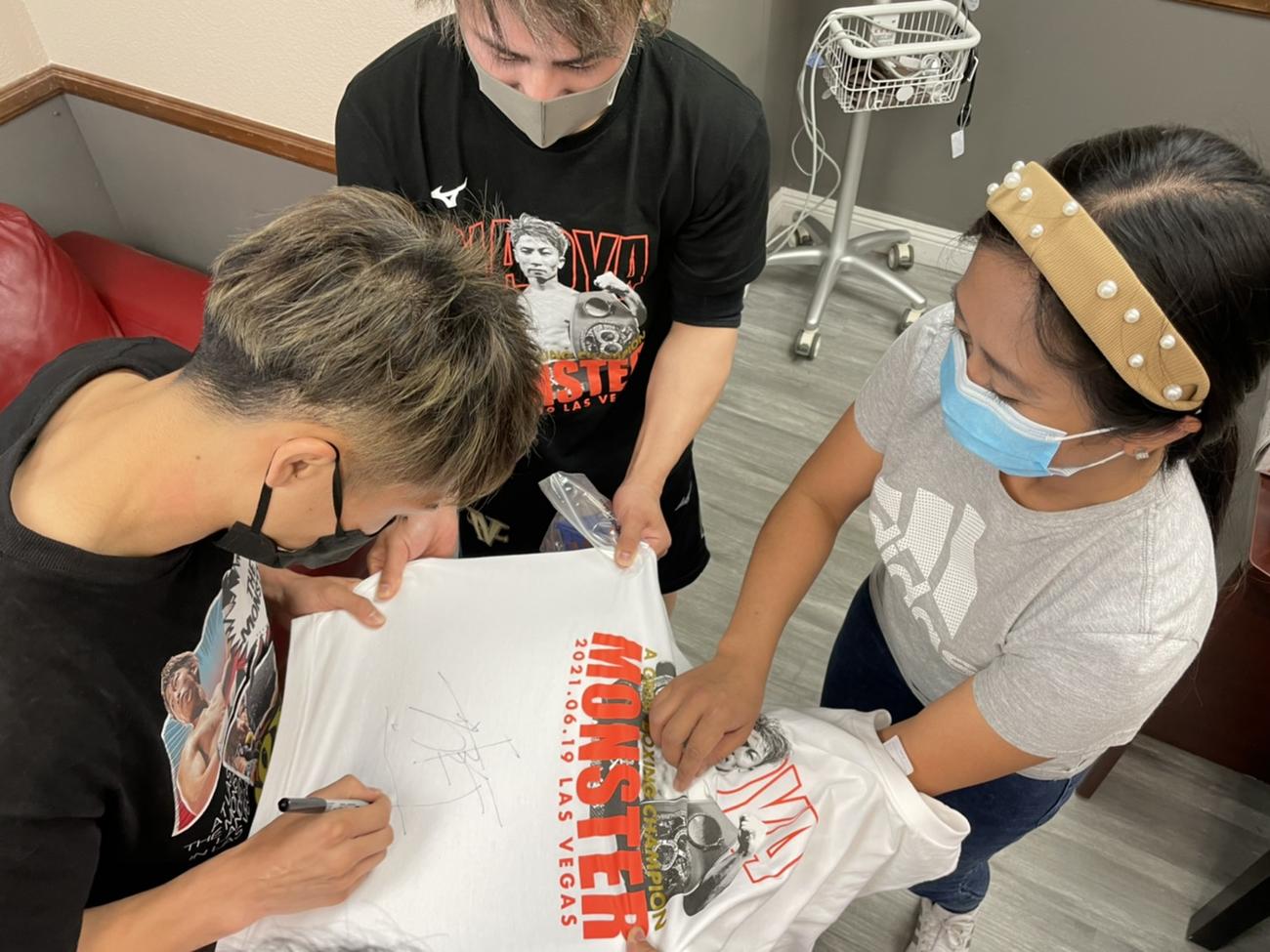 ボクシングファンだという看護師（手前右）にTシャツをプレゼントし、サインをする井上尚弥
（大橋ジム提供）