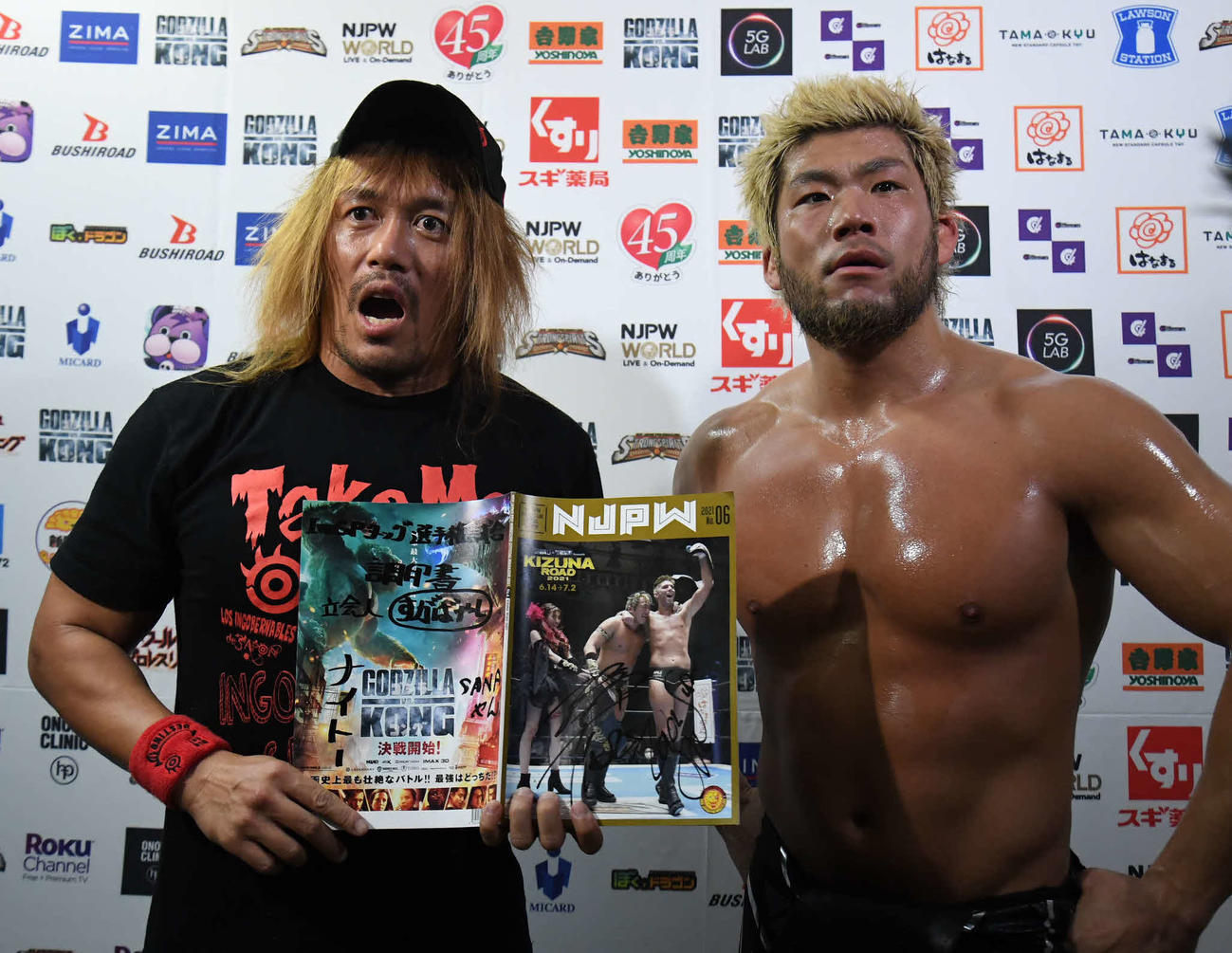 新日本プロレス後楽園大会　IWGPタッグ王者のタイチ、ザック・セイバーJr．組にサインをもらった内藤哲也（左）は「調印書」と書いたパンフレットを広げて見せる。右はSANADA（新日本プロレス提供）