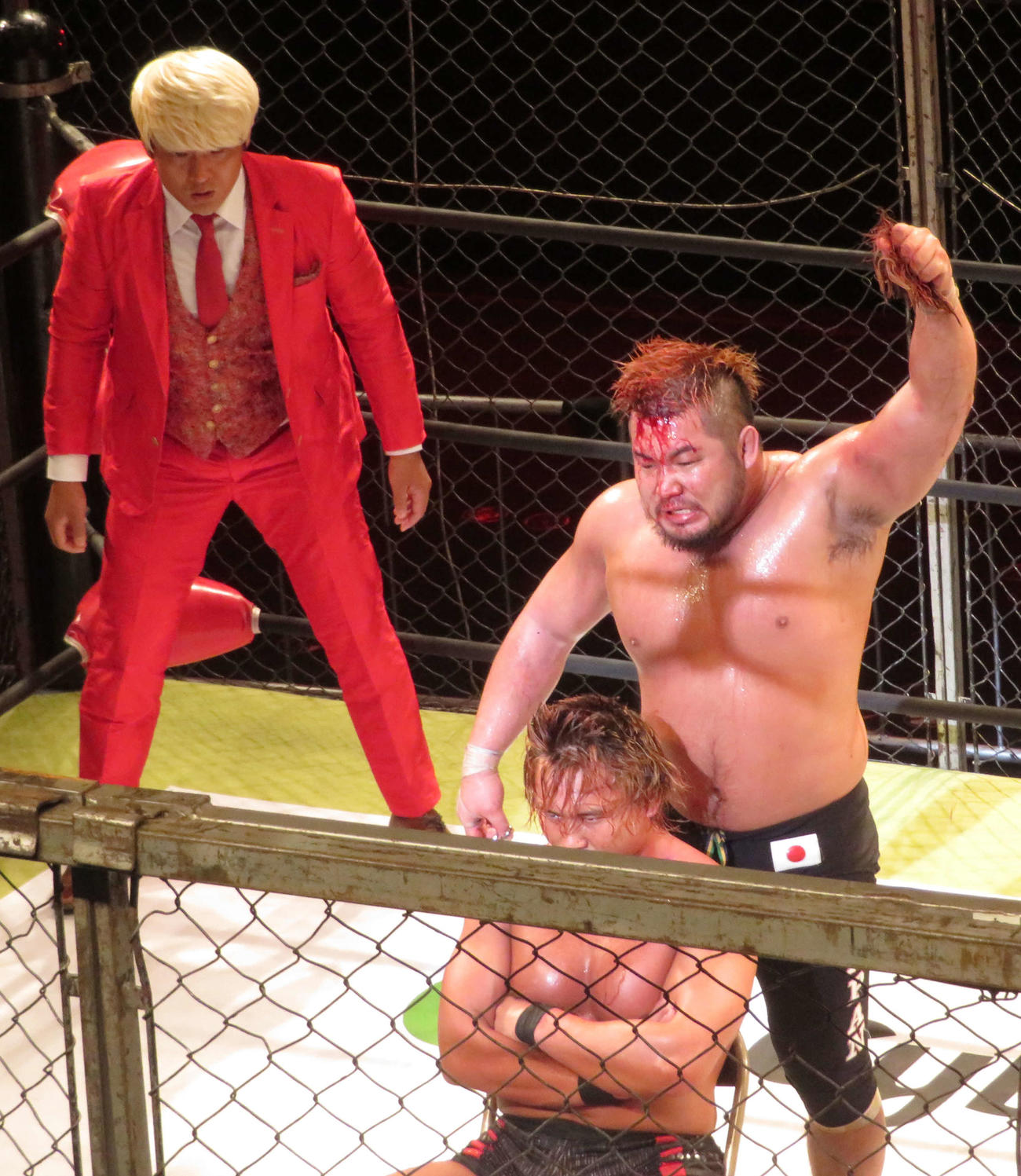 プロレスリング・ノア　敗者髪切り金網デスマッチに勝利したマサ北宮は、中嶋勝彦の髪を手に持ち、高々と突き上げる。後方は立会人の拳王（撮影・松熊洋介）