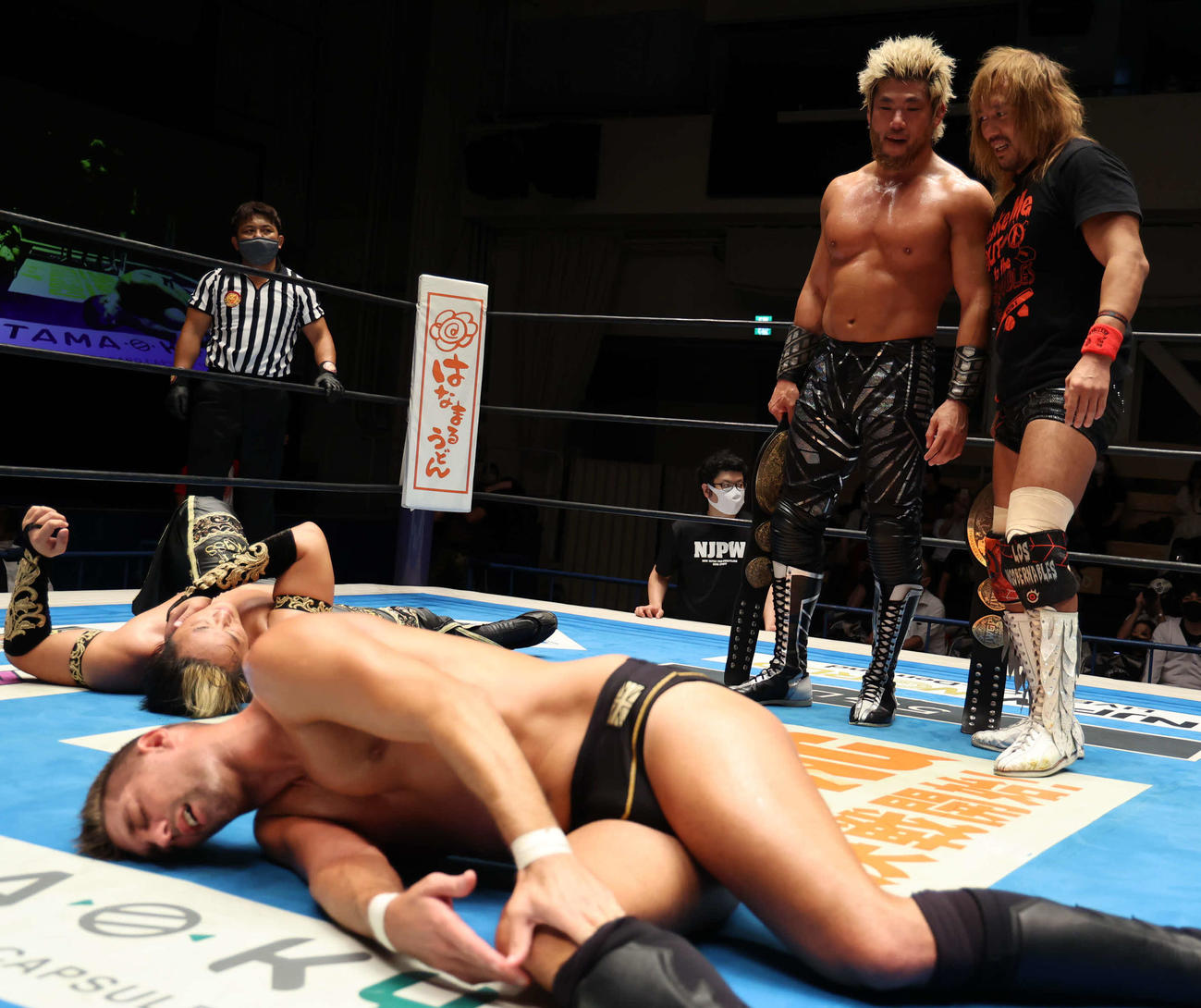 新日本プロレス後楽園大会　試合後、リングに横たわるタイチ（奥）とザック・セイバーJr．（手前）を見て不敵な笑みを浮かべる内藤哲也（後方右）とSANADA（同左）（新日本プロレス提供）