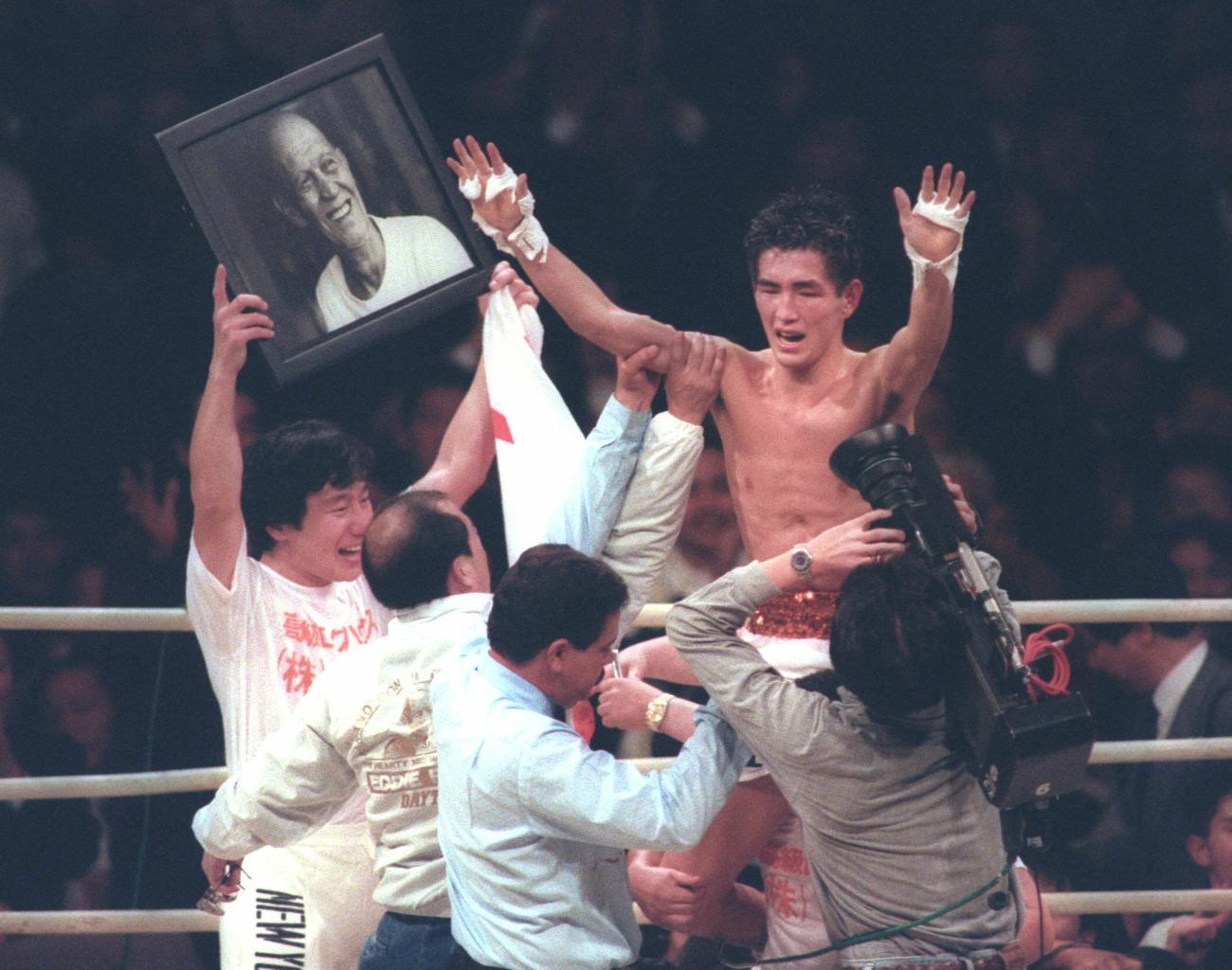 1991年12月17日、2階級を制覇した井岡弘樹（右）はトレーナーだった故タウンゼントさんの写真の横で喜ぶ