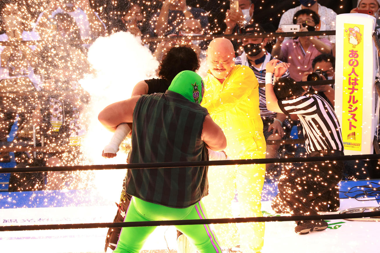 スーパー・ササダンゴ・マシン（手前）に抑えられた大仁田（中央）に電流バットを浴びせるクロちゃん（撮影・中島郁夫）