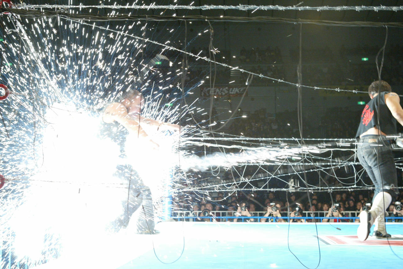 大仁田厚（右）に有刺鉄線に投げられ爆発する越中詩郎（2003年3月1日撮影）