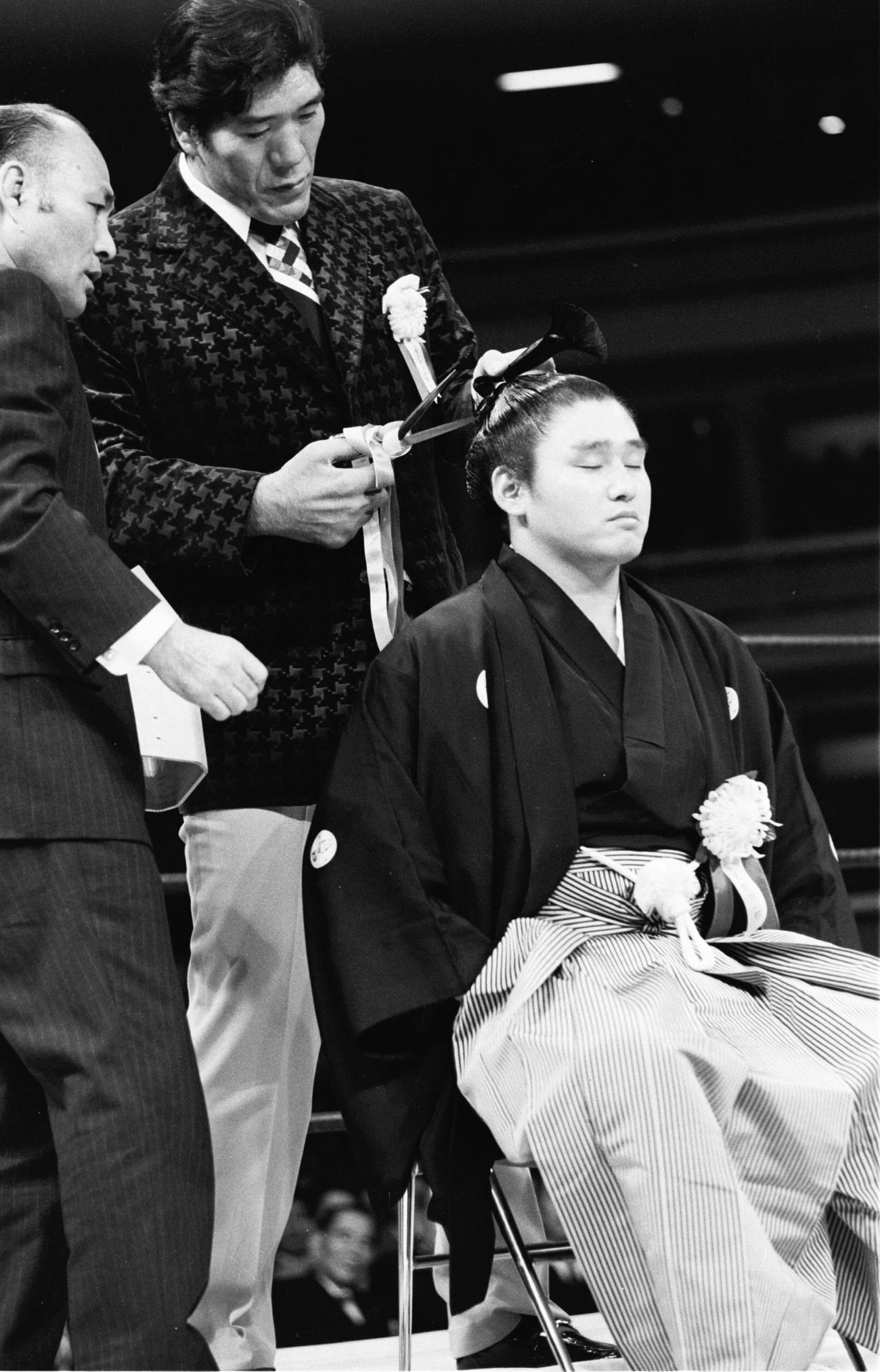 1976年12月、リング上で断髪式を行いジャイアント馬場さん（中央）にはさみを入れられる天龍