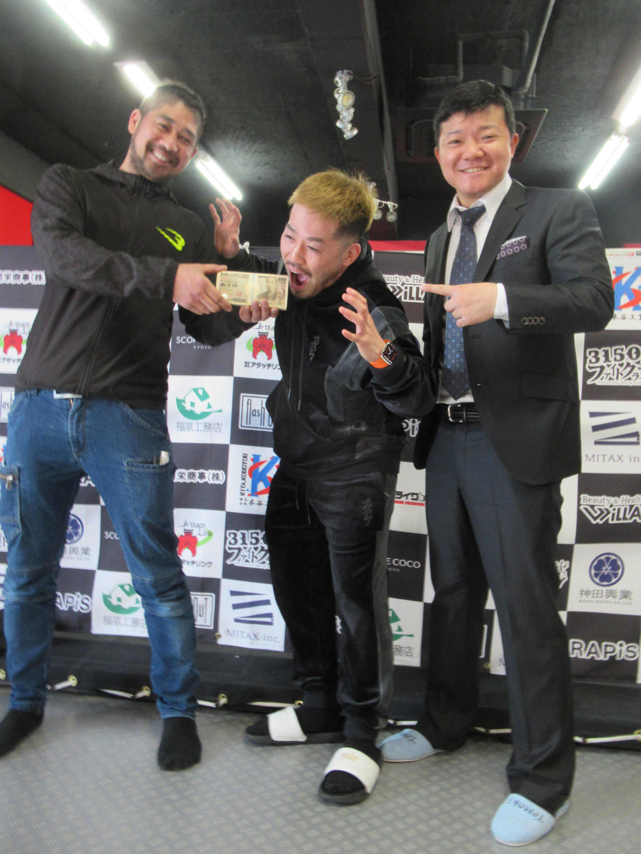 KO勝利のボーナス100万円にかぶりつく元世界王者の宮崎（中央）。右は元世界王者の亀田大毅3150FC副会長（撮影・実藤健一）
